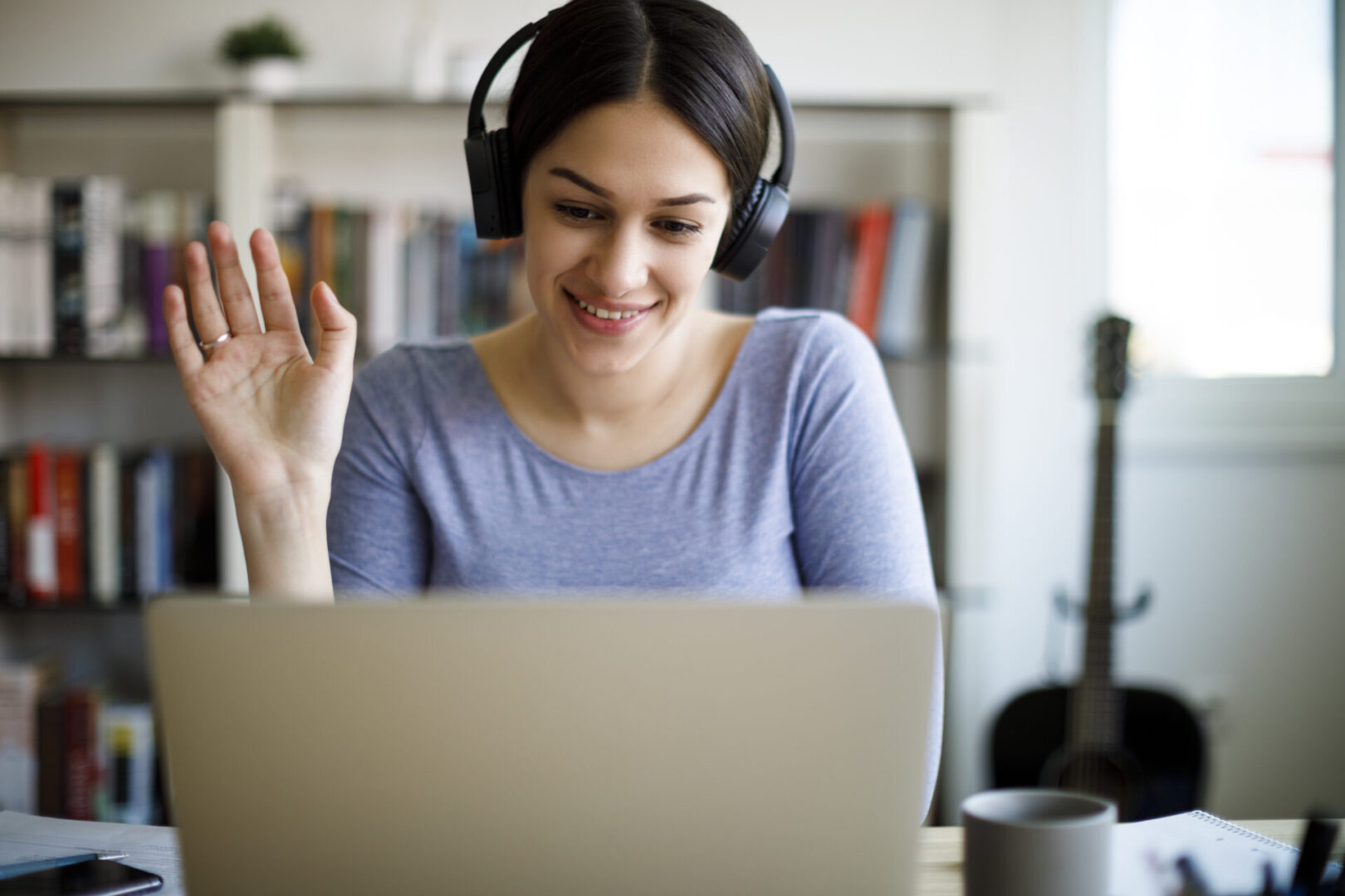 Young smiling woman having video call on laptop computer at home