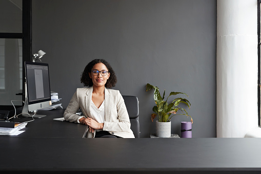 Portrait of smiling businesswoman sitting at modern office desk
